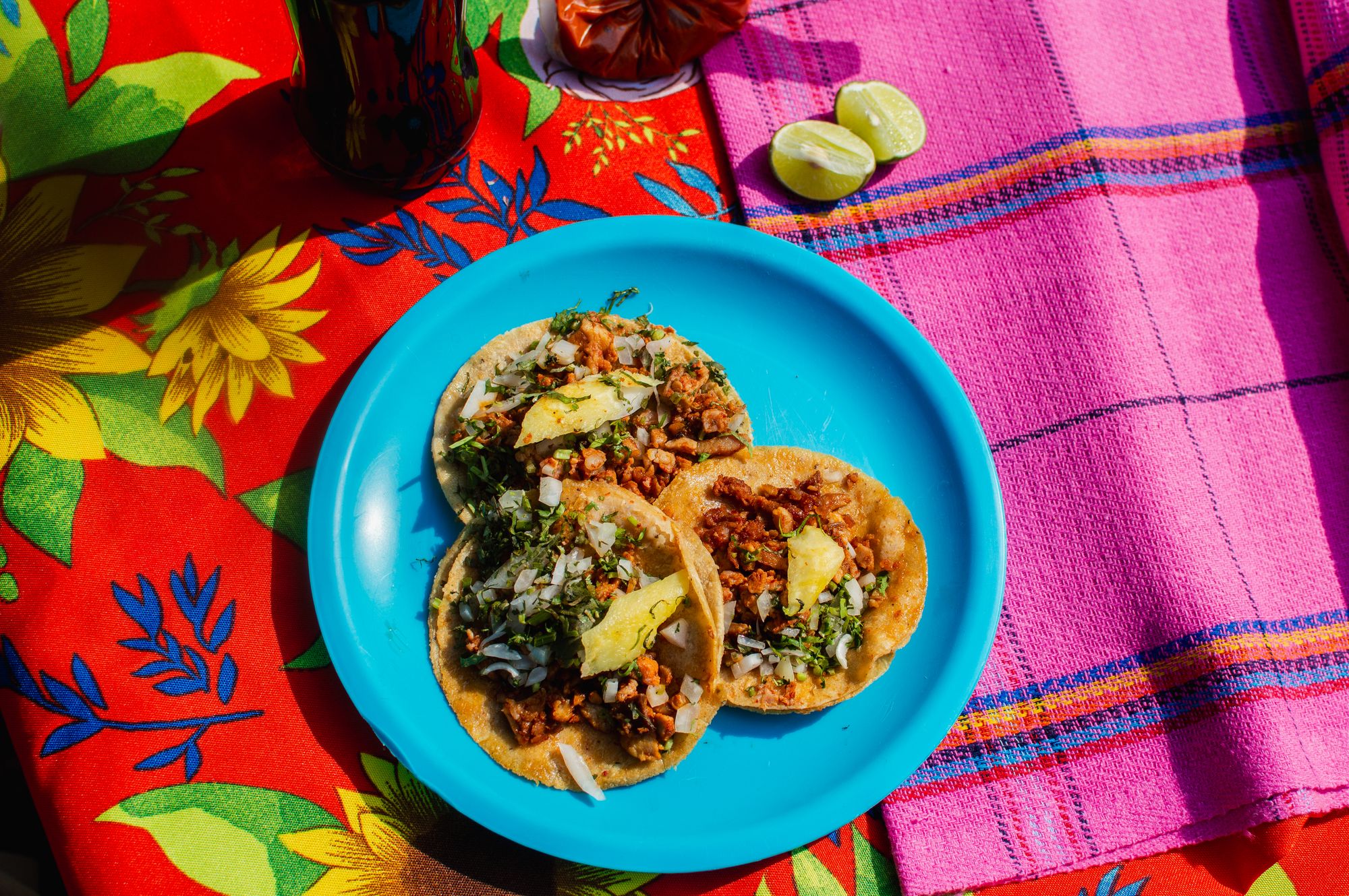 Tacos sobre plato turquesa y mantel colorido